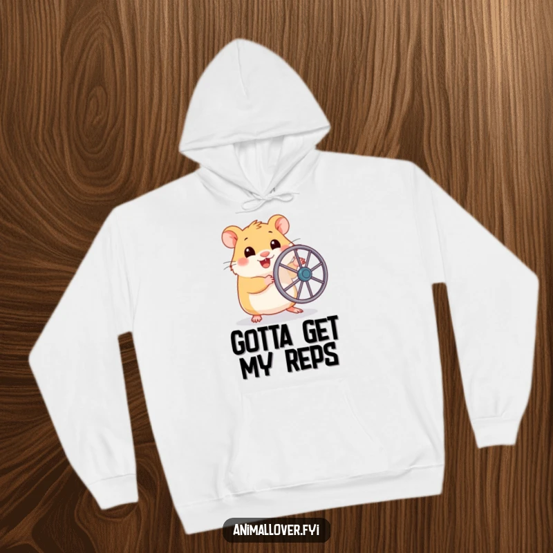 Funny hoodie showcasing a happy hamster holding a tiny running wheel, about to embark on a lively, miniature fitness journey.